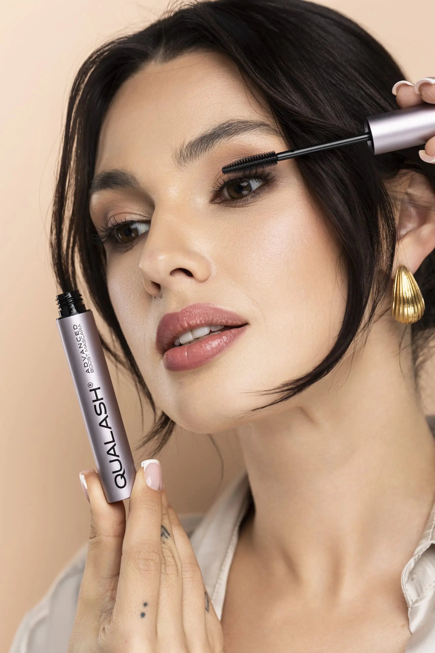 alt
Smilende kvinde holder QUALASH Advanced Mascara Volume Max efter påføring – Trin 2
