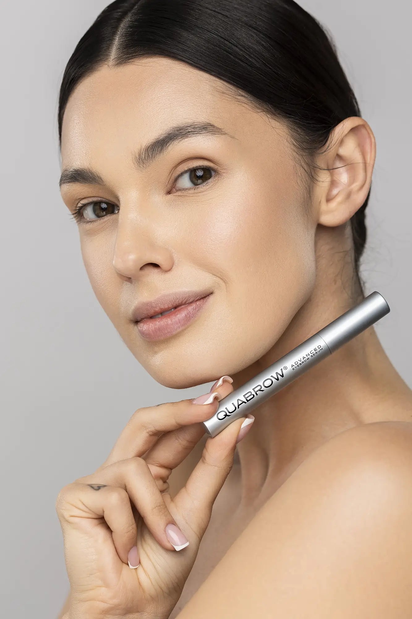 Woman påfører QUABROW Advanced Eyebrow Serum direkte på brynlinjen med applikatoren – trin 1