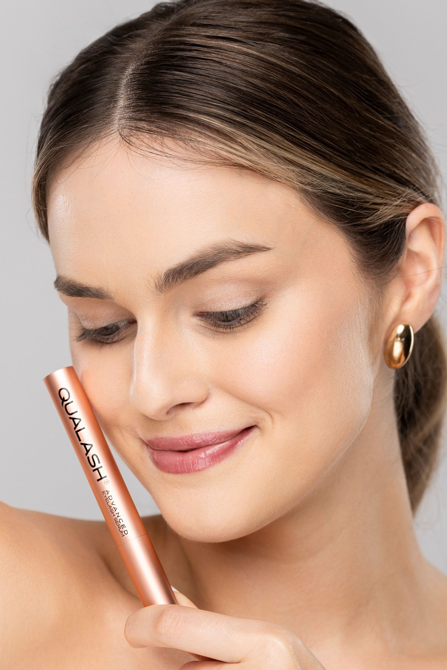 Woman with natural makeup and enhanced lashes using QUALASH lash serum
